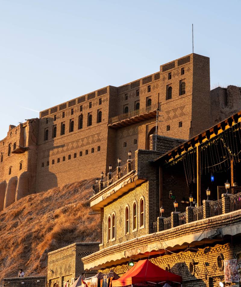 Iraq, Iraqi Kurdistan, Arbil, Erbil. View from a café looking over the street on the first floor. In the background is Erbil Qalat citadel at sunset.